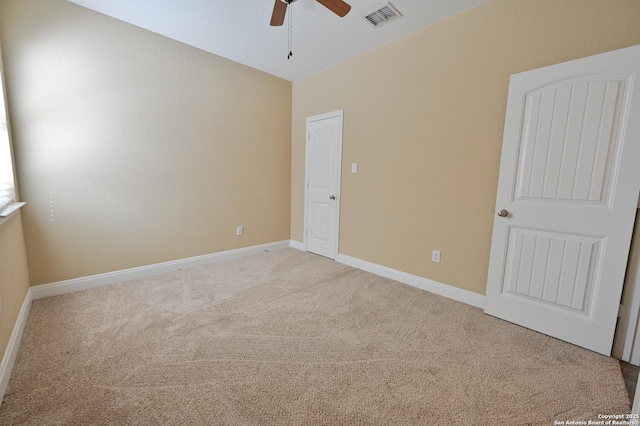 interior space with visible vents, baseboards, light colored carpet, and ceiling fan