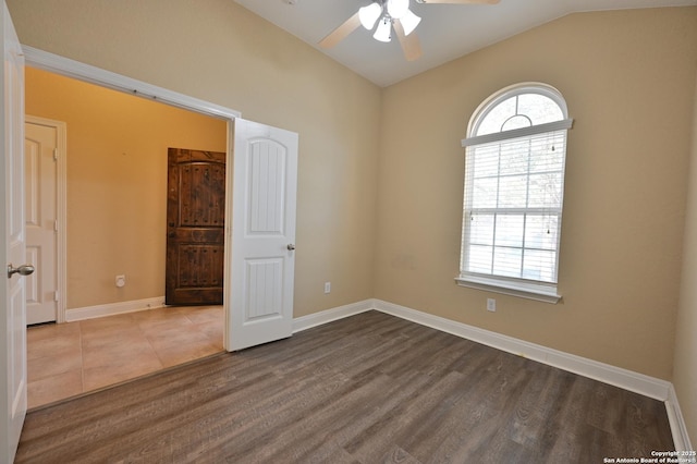 empty room with vaulted ceiling, wood finished floors, baseboards, and a wealth of natural light