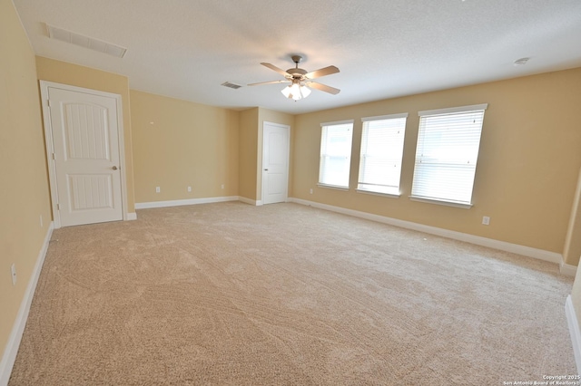 unfurnished room with visible vents, baseboards, light colored carpet, and ceiling fan