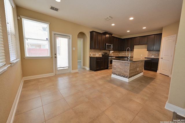 kitchen featuring tasteful backsplash, arched walkways, visible vents, and appliances with stainless steel finishes