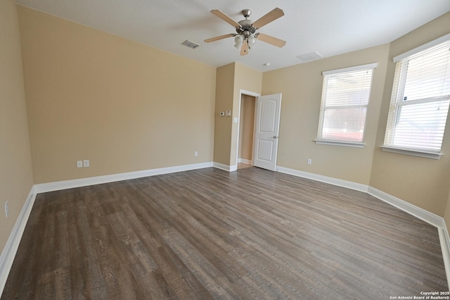 empty room with visible vents, a ceiling fan, baseboards, and dark wood-style flooring