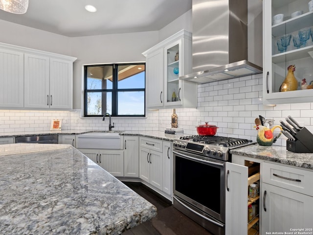 kitchen with stainless steel gas range, a sink, white cabinets, dishwasher, and wall chimney exhaust hood