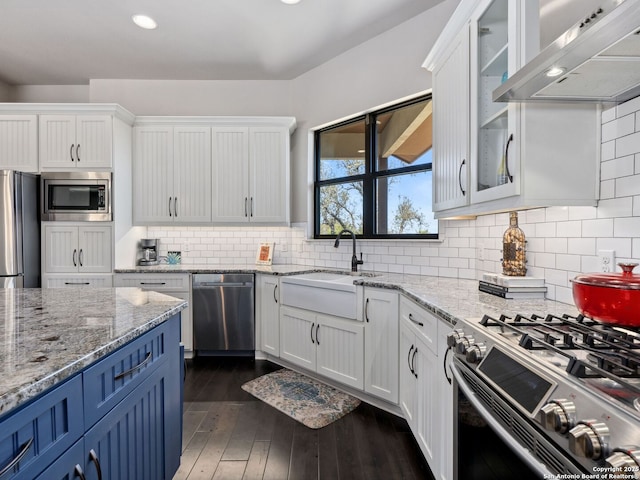 kitchen featuring white cabinets, stainless steel appliances, wall chimney exhaust hood, and a sink