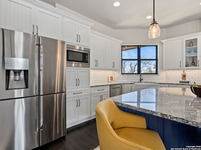 kitchen featuring backsplash, appliances with stainless steel finishes, light stone countertops, and a sink