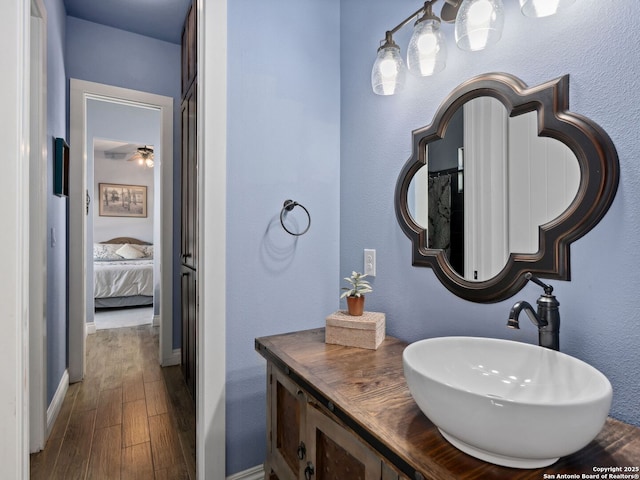 ensuite bathroom featuring connected bathroom, baseboards, wood finished floors, and vanity