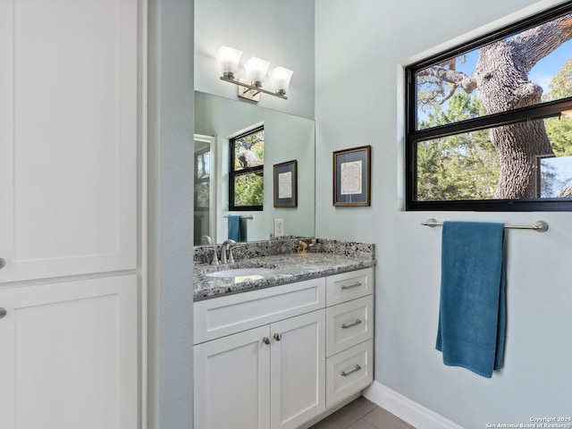 bathroom with a wealth of natural light, baseboards, vanity, and tile patterned floors