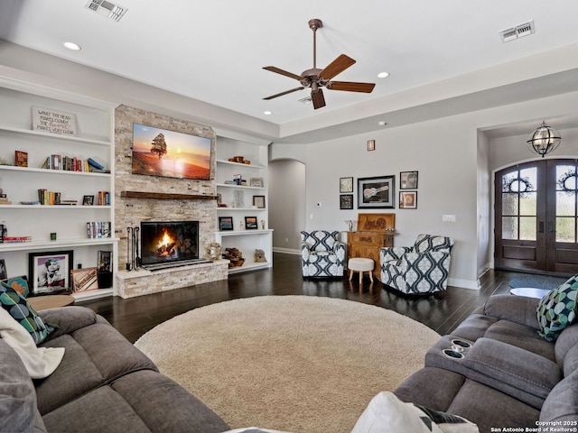 living area with dark wood finished floors, visible vents, arched walkways, and a fireplace