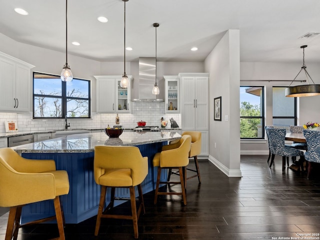 kitchen with visible vents, backsplash, wall chimney range hood, dark wood-style floors, and a sink