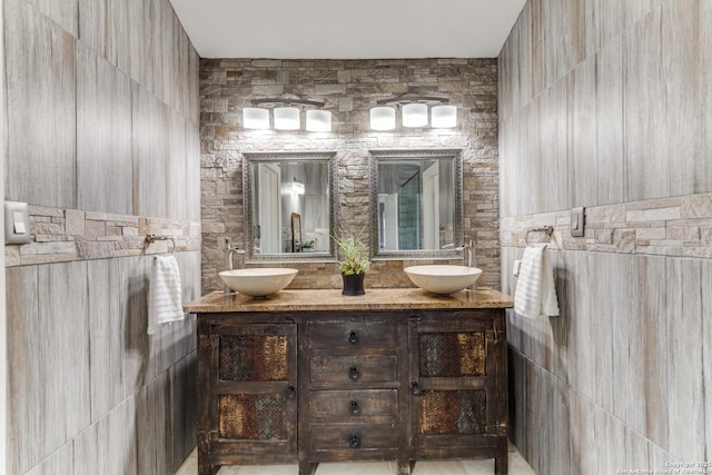 bathroom with tile walls, double vanity, and a sink