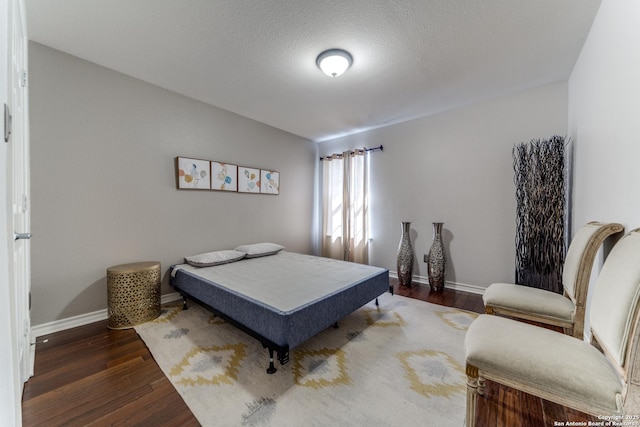 bedroom with wood finished floors, baseboards, and a textured ceiling