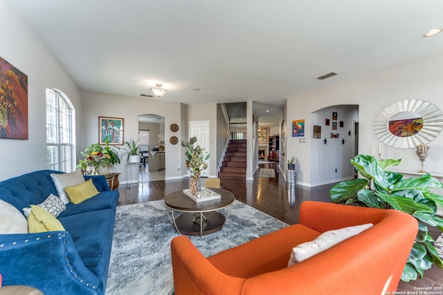 living area featuring stairs, visible vents, wood finished floors, and arched walkways