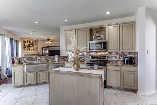 kitchen featuring a sink, light stone counters, tasteful backsplash, appliances with stainless steel finishes, and a peninsula