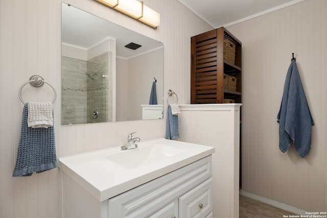 bathroom featuring ornamental molding, vanity, and a tile shower