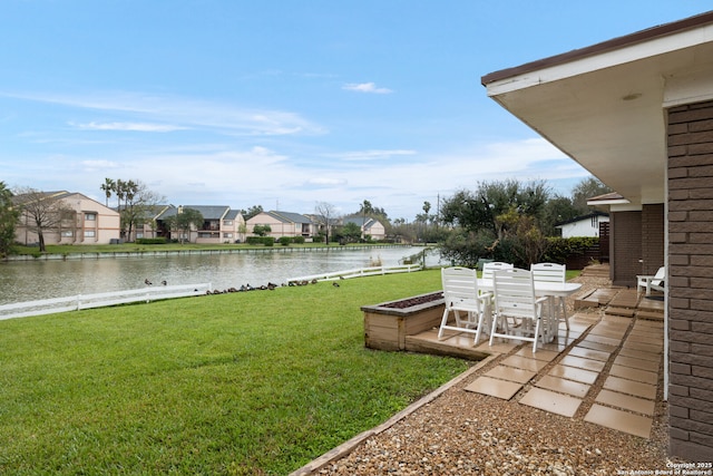view of yard with a patio area, a residential view, outdoor dining area, and a water view