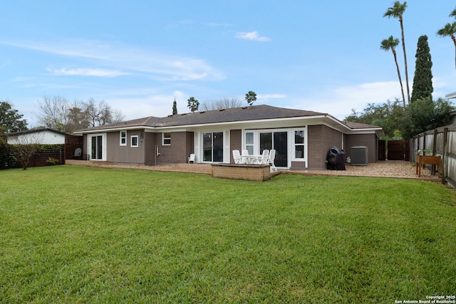 back of property with a lawn, a patio, central AC, a fenced backyard, and brick siding