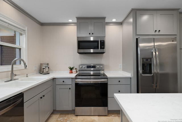 kitchen featuring recessed lighting, gray cabinets, a sink, stainless steel appliances, and light countertops