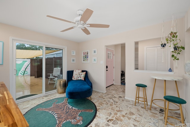 sitting room with a ceiling fan and baseboards
