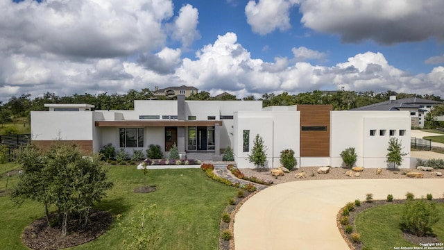 contemporary house featuring concrete driveway, fence, a front lawn, and stucco siding