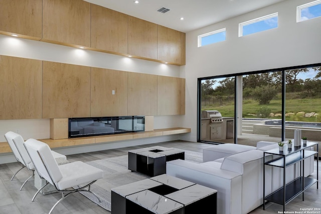 living room with a glass covered fireplace, a high ceiling, recessed lighting, and visible vents