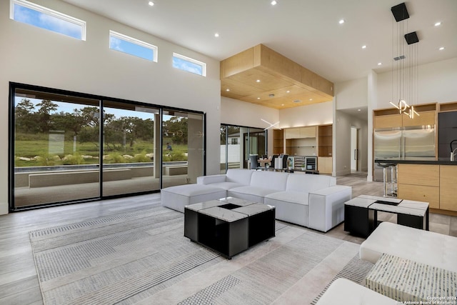 living room with light wood finished floors, recessed lighting, and a towering ceiling