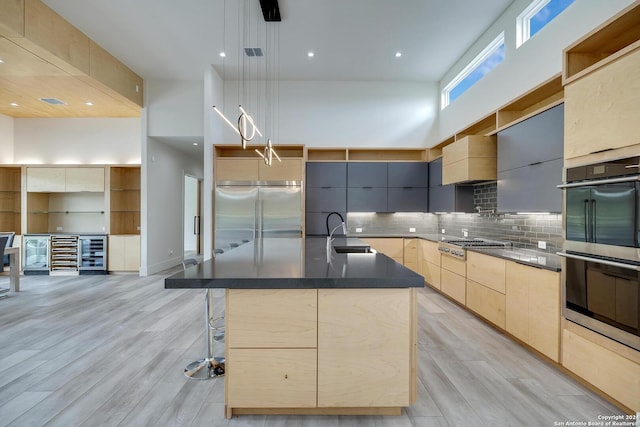 kitchen with light brown cabinetry, a high ceiling, stainless steel appliances, modern cabinets, and a sink