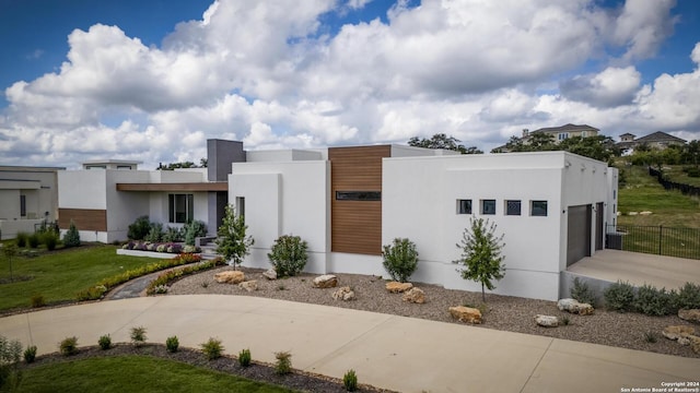 contemporary home with a garage, driveway, and stucco siding