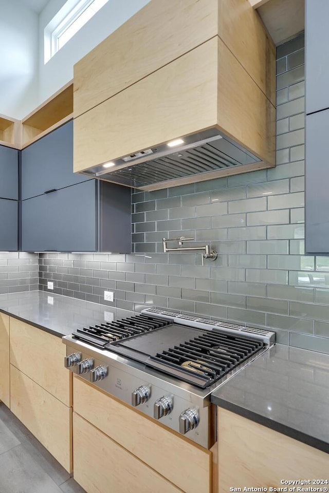 kitchen featuring stainless steel gas cooktop, dark stone counters, decorative backsplash, custom range hood, and modern cabinets