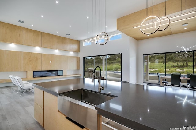 kitchen with visible vents, light brown cabinets, open floor plan, and a sink