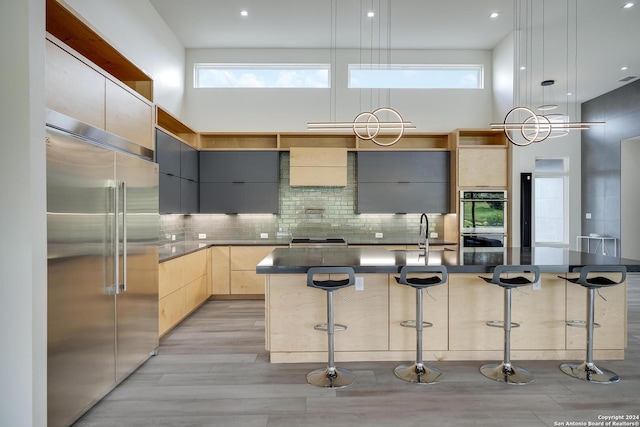 kitchen with a towering ceiling, modern cabinets, appliances with stainless steel finishes, and a sink