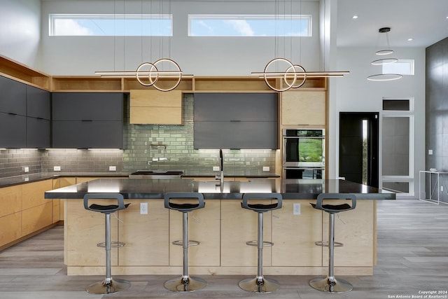 kitchen with stainless steel double oven, a high ceiling, a sink, dark countertops, and modern cabinets