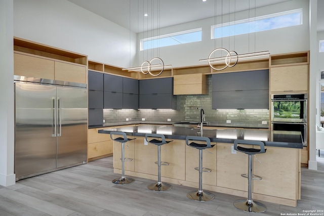 kitchen with dark countertops, a high ceiling, stainless steel appliances, modern cabinets, and a sink