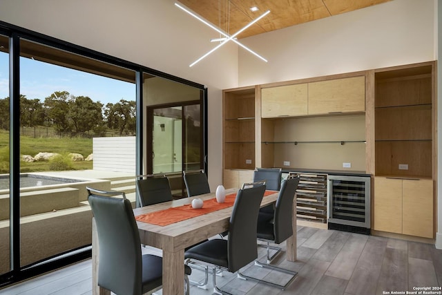 interior space featuring an inviting chandelier, wine cooler, a high ceiling, and light wood finished floors