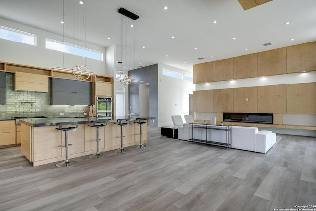 kitchen with a large island, light brown cabinets, modern cabinets, and light wood-type flooring