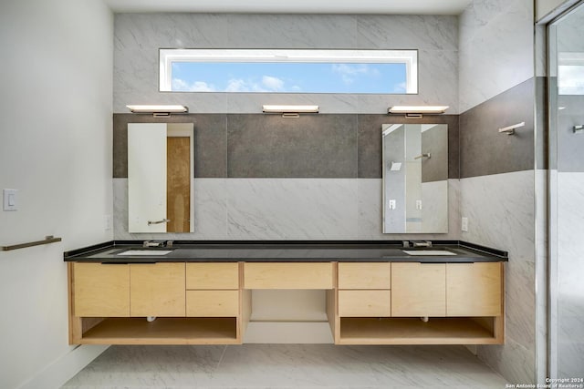 bathroom with a wealth of natural light, marble finish floor, and double vanity