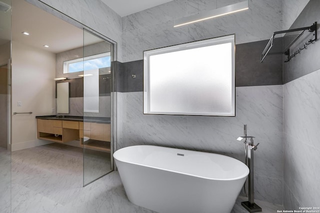 full bathroom featuring a soaking tub, marble finish floor, and vanity