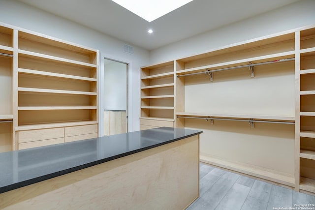 walk in closet featuring a skylight, visible vents, and wood finished floors