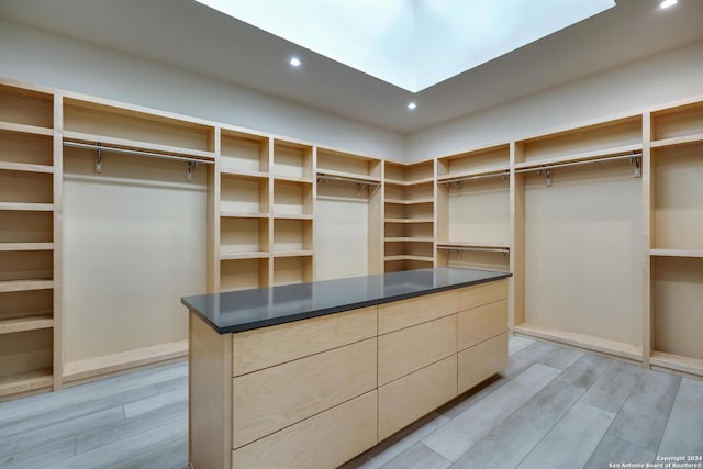 walk in closet featuring a skylight and light wood finished floors