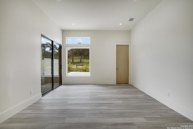 spare room with wood finished floors, visible vents, and baseboards