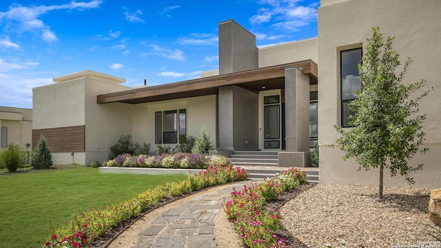 doorway to property with a yard and stucco siding