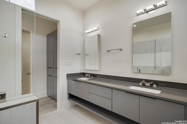 bathroom featuring double vanity, a walk in shower, and a sink