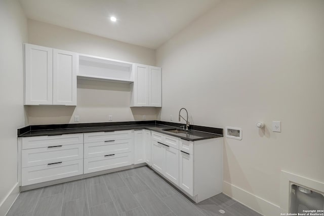 kitchen featuring a sink, open shelves, dark countertops, and white cabinets