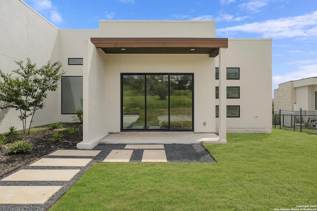 back of property with a yard, a patio, stucco siding, and fence