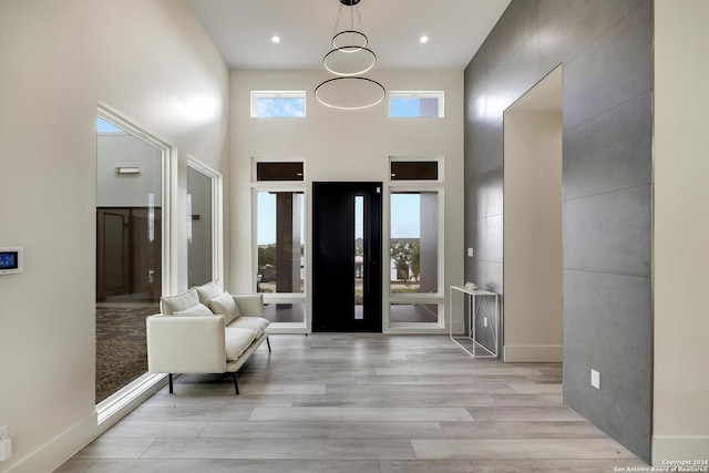 foyer with light wood finished floors, recessed lighting, a high ceiling, and baseboards