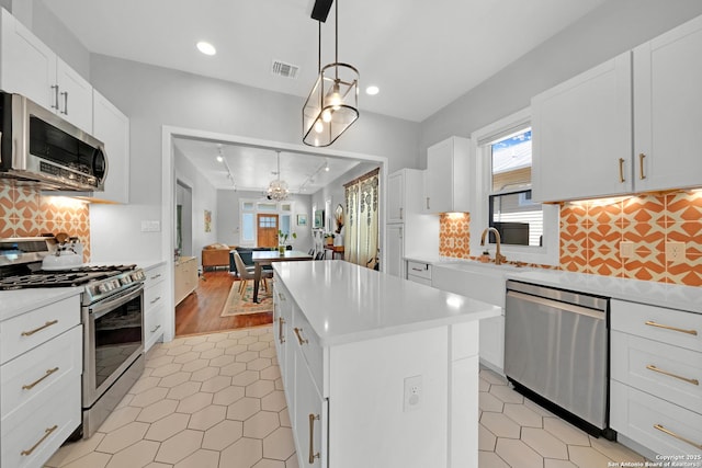 kitchen featuring visible vents, a kitchen island, light tile patterned flooring, stainless steel appliances, and light countertops