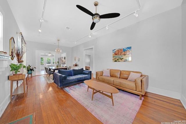 living area featuring baseboards, ceiling fan, track lighting, and hardwood / wood-style flooring