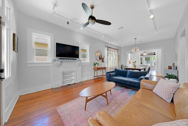 living room with visible vents, track lighting, a ceiling fan, and wood finished floors