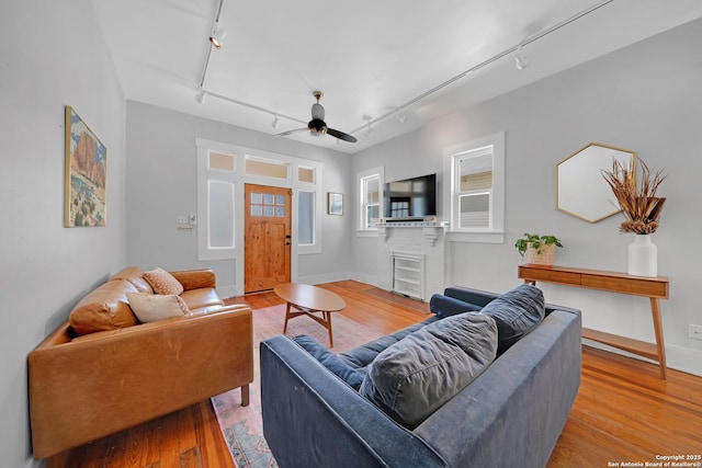 living area featuring rail lighting, a ceiling fan, and wood finished floors