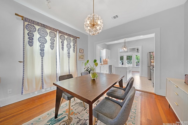 dining area with visible vents, baseboards, an inviting chandelier, and light wood-style flooring