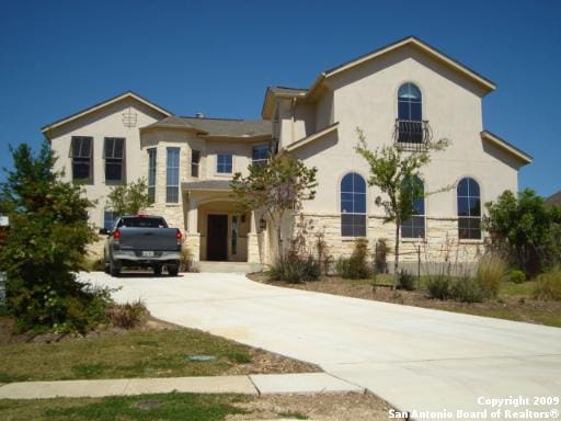 view of front of house with concrete driveway, stone siding, and stucco siding