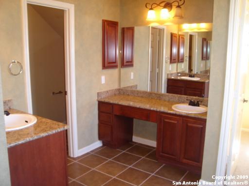 full bathroom featuring tile patterned floors, two vanities, baseboards, and a sink